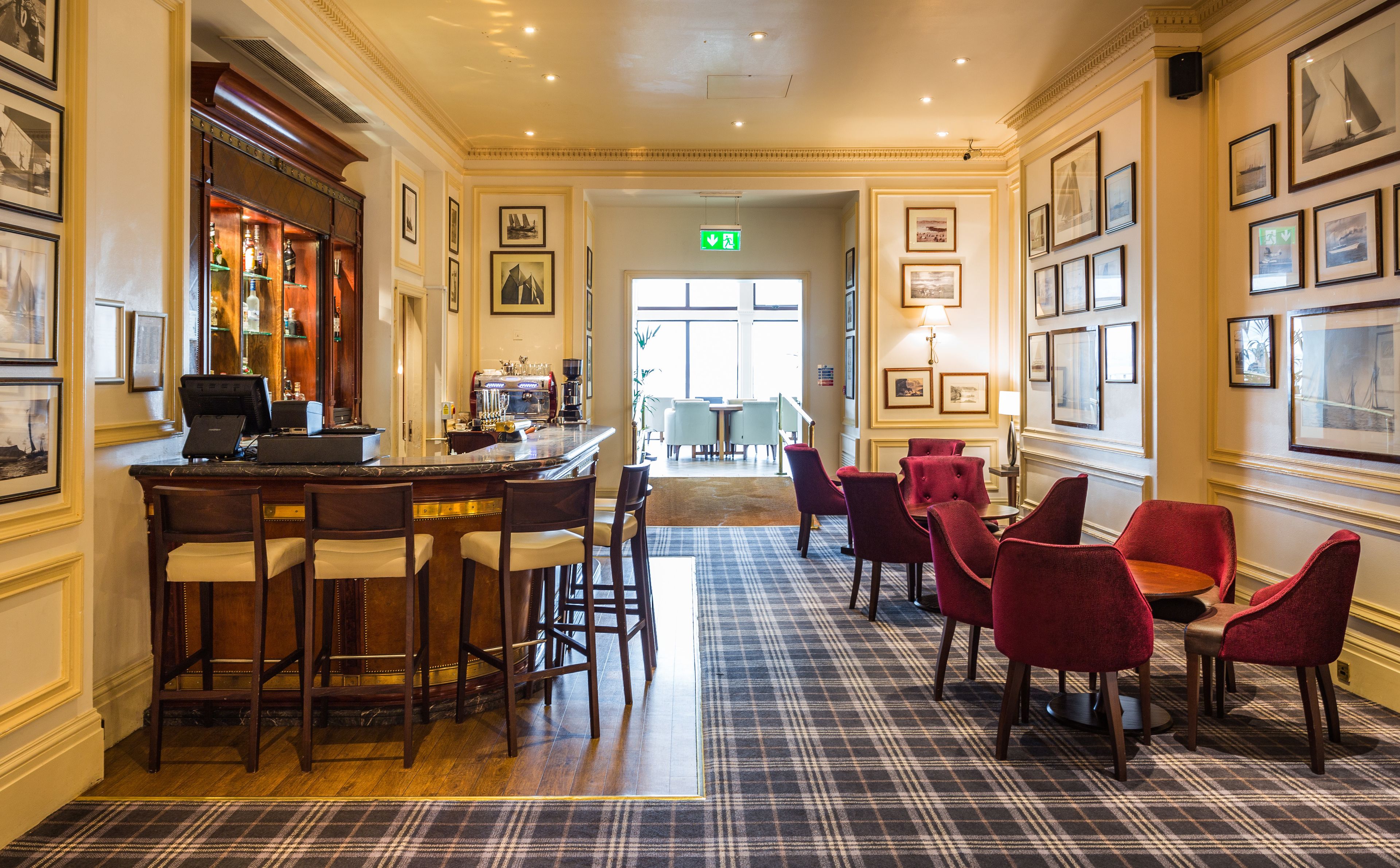 A hotel lobby with a bar area, seating, and framed artwork on the walls.