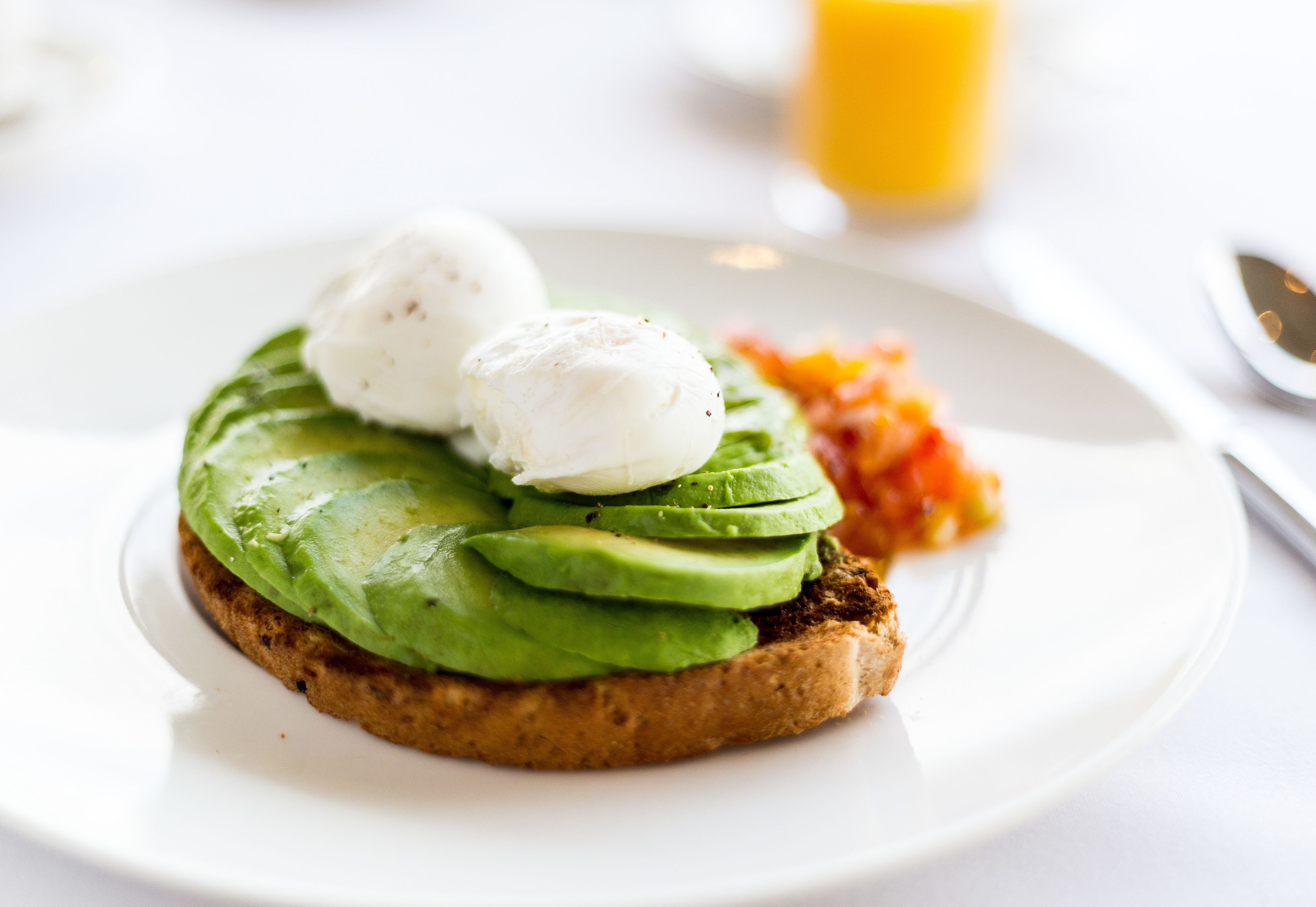 A breakfast plate with avocado toast, poached eggs, and a side of vegetables.