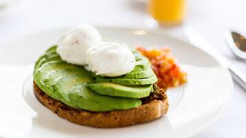A breakfast plate with avocado toast, poached eggs, and a side of vegetables.