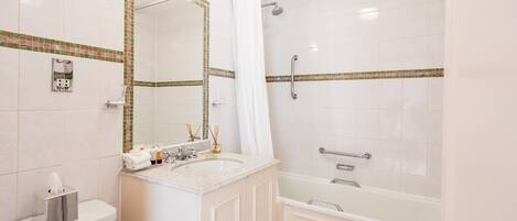 A bathroom with a toilet, sink, mirror, and bathtub.