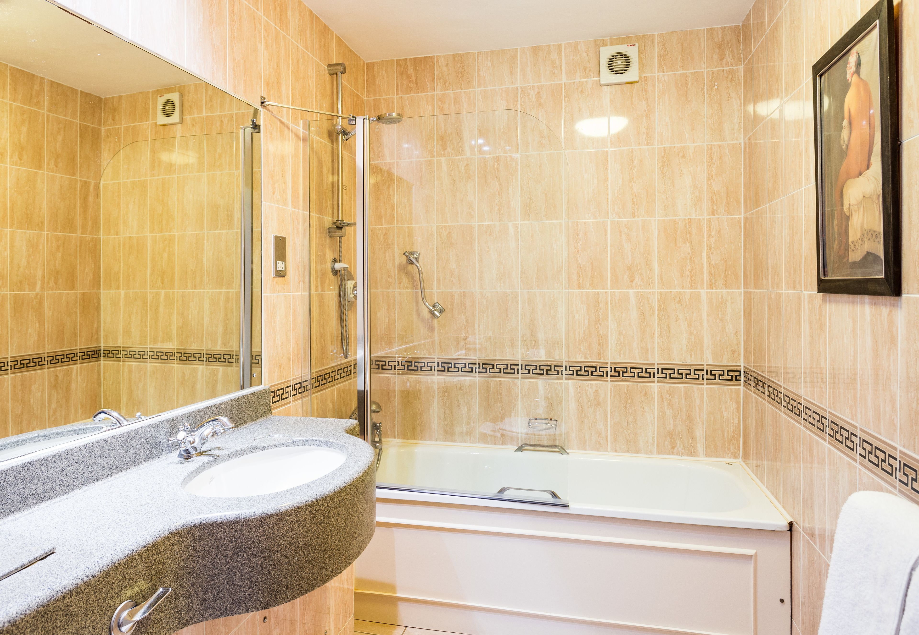 A bathroom with a granite sink, a bathtub, and a shower.