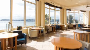 A spacious indoor area with large windows offering a view of a body of water and distant landscape.