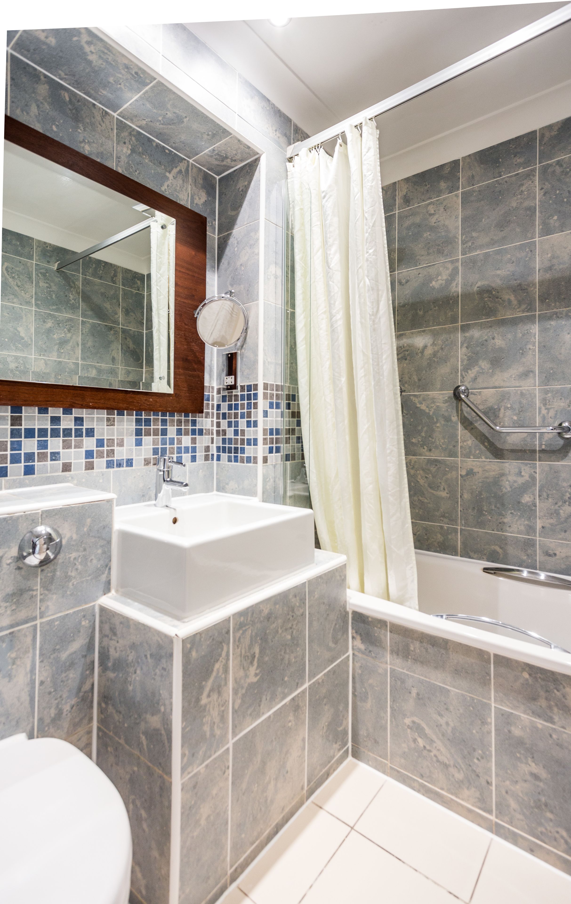A modern bathroom with a white sink, a mirror, and a shower area with a glass door.
