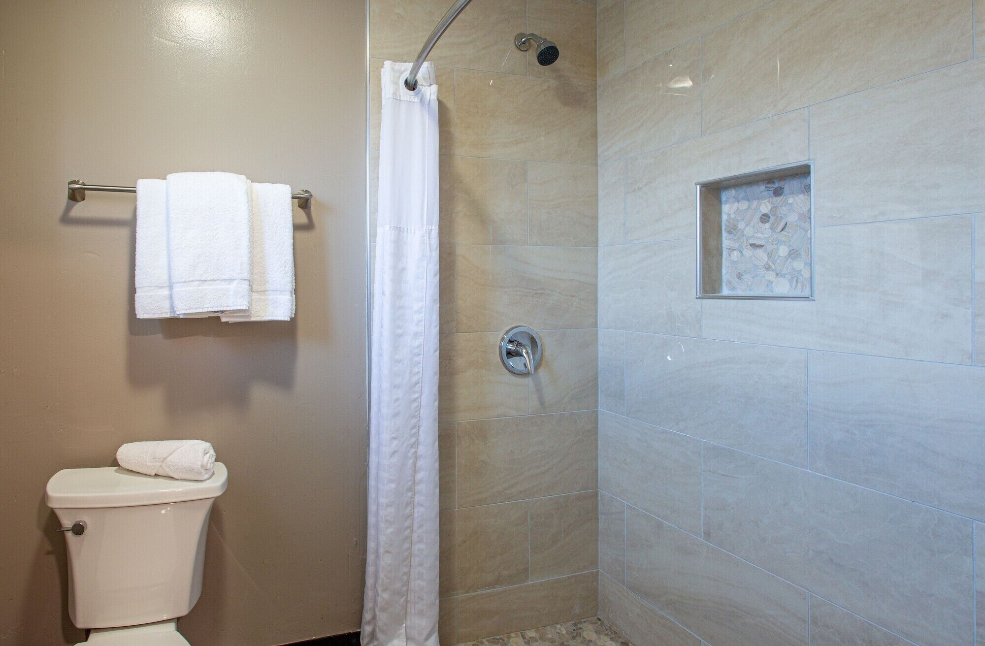 A bathroom with a shower, toilet, and a towel rack.