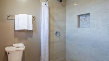 A bathroom with a shower, toilet, and a towel rack.