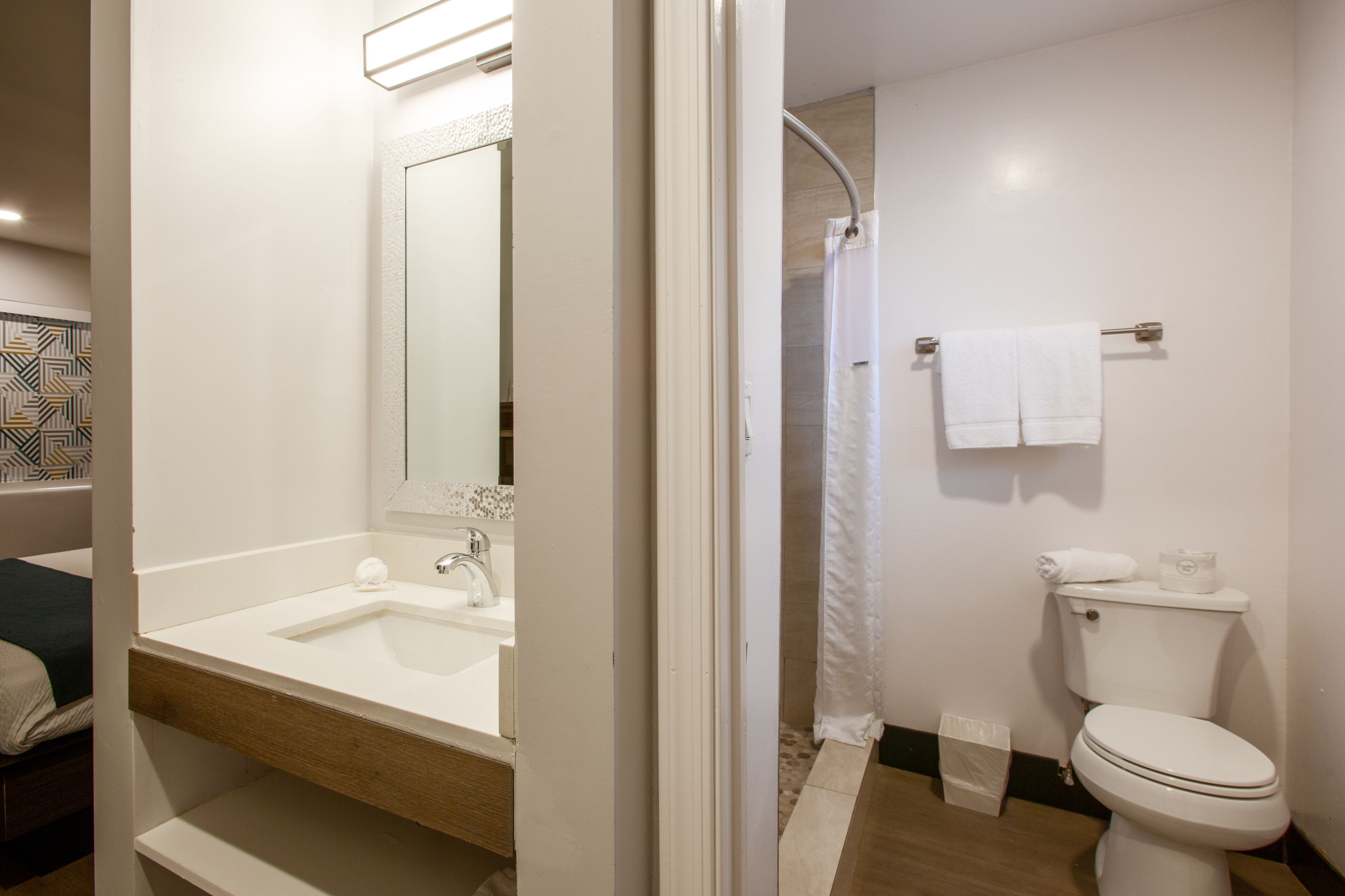 A modern bathroom with a sink, mirror, toilet, and shower curtain.