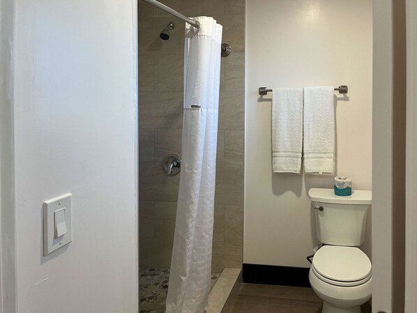 A bathroom with a shower, toilet, and towel rack.