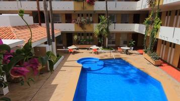 A courtyard with a swimming pool, outdoor seating, and potted plants.