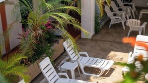 A patio area with white lounge chairs and potted plants. - Azteca Inn (Mazatlán)