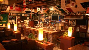 A bar area with a counter, seating, and various decorations including flags and memorabilia. - Azteca Inn (Mazatlán)