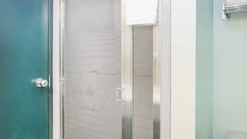 Ein Badezimmer mit Duschkabine aus Glas, Toilette und Handtuchhalter.