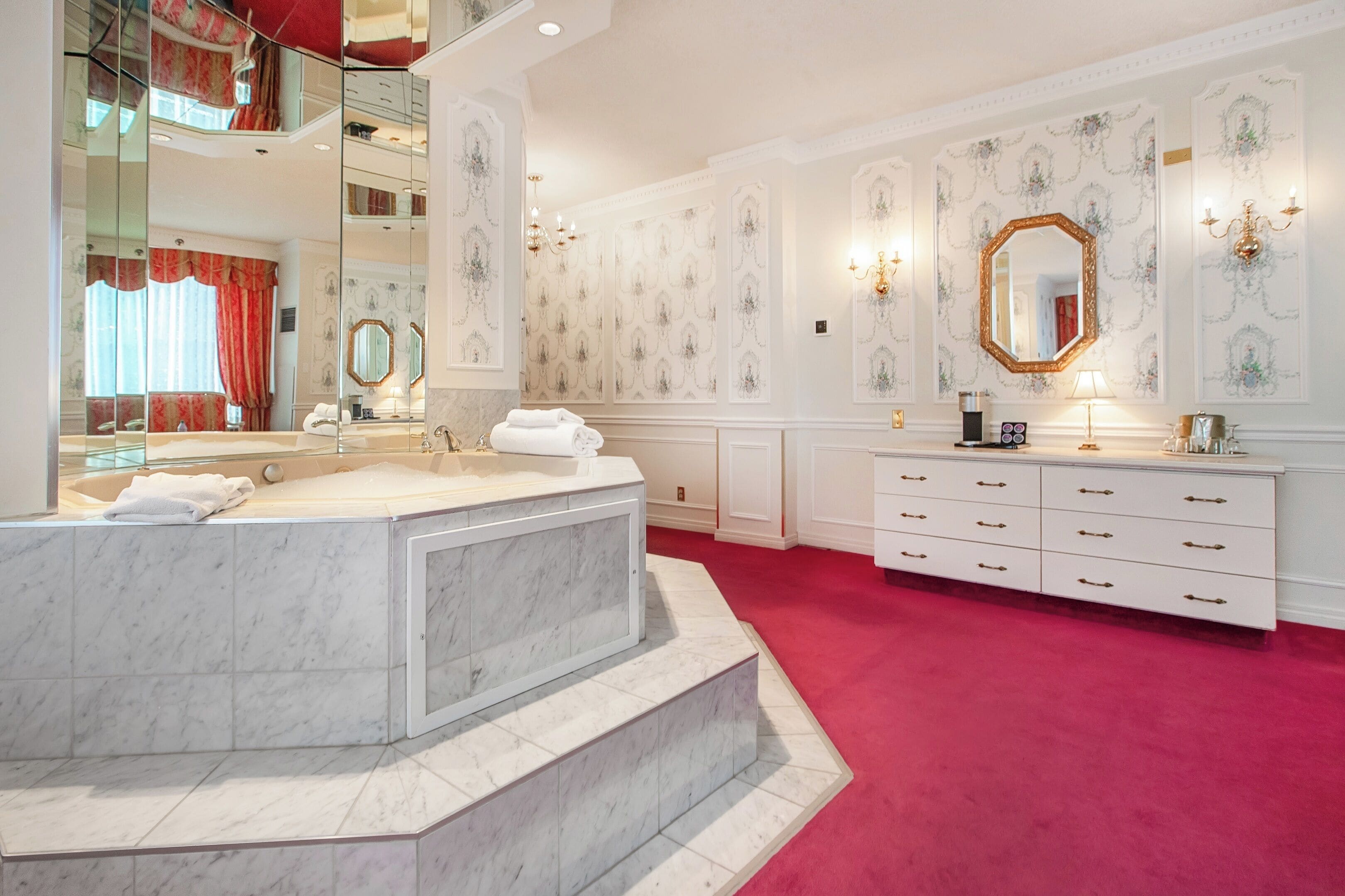 Une salle de bain luxueuse avec une grande baignoire en marbre, un meuble-lavabo doté de nombreux tiroirs et un grand miroir.