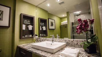 A modern bathroom with a large mirror, a granite countertop, and a white sink.