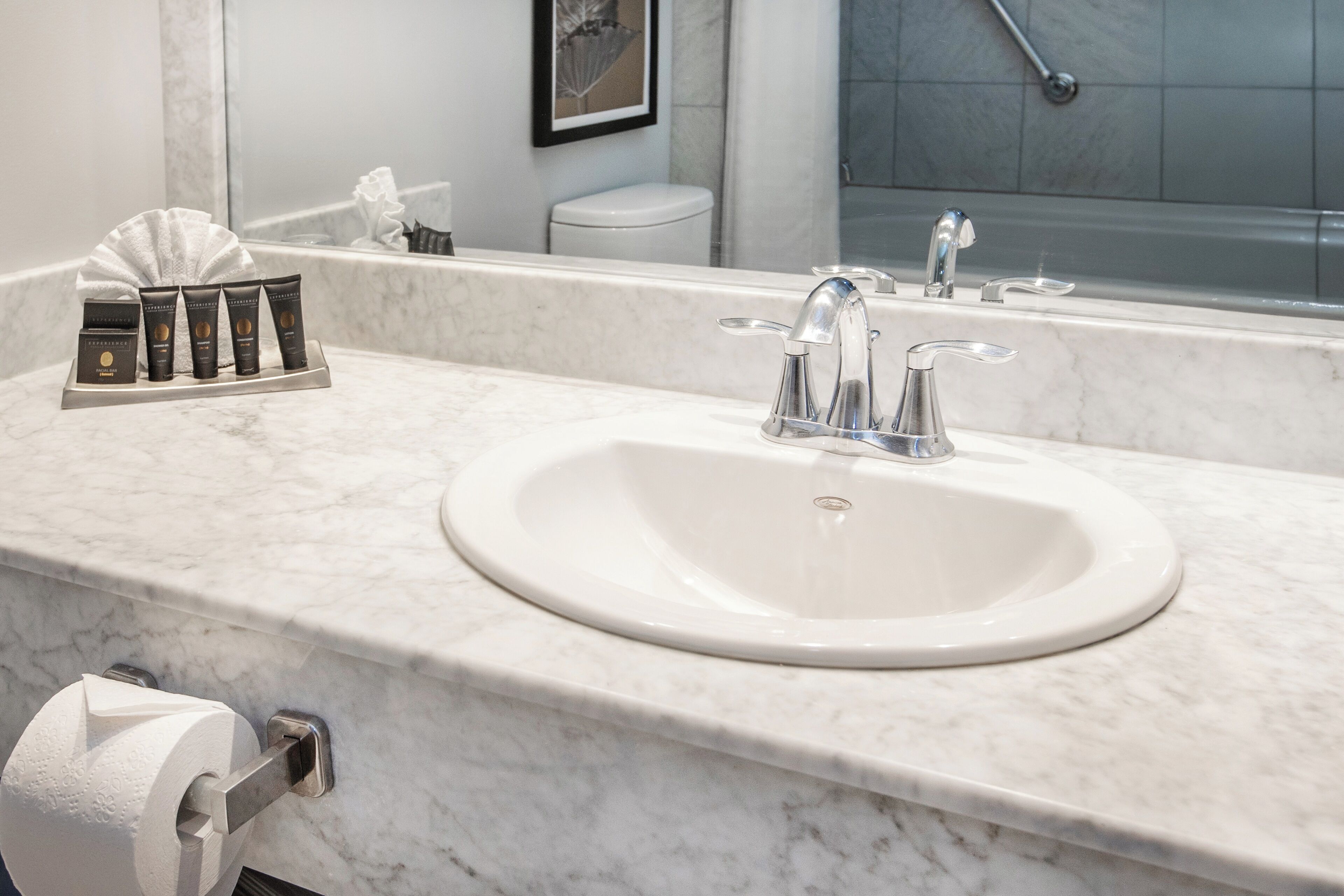 A bathroom with a white sink, a mirror, a towel rack, and a toilet.