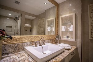 A bathroom with a large mirror, a sink, and a glass shelf with towels.
