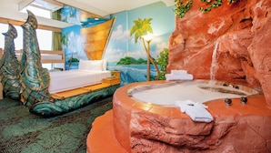 Une chambre avec un lit, une baignoire et une fresque représentant un paysage tropical.
