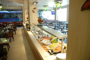 A buffet area with various food items and a seating area with tables and chairs.