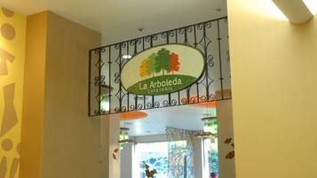 A cafe sign with a tree and the name "La Arboleda".
