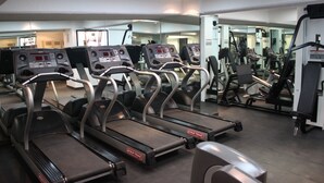 Une salle de sport équipée de plusieurs tapis de course et d’appareils d’exercice.