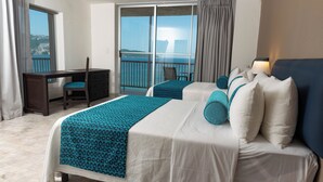 Habitación de hotel con cama, escritorio y vista al mar.