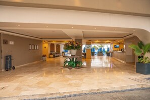 A spacious lobby with a marble floor, a reception desk, and potted plants.