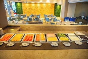 A buffet area with various food options and a seating area in the background.