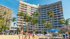 Una playa con palmeras y un hotel al fondo.