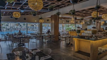A restaurant with outdoor seating, a pool view, and hanging plants.