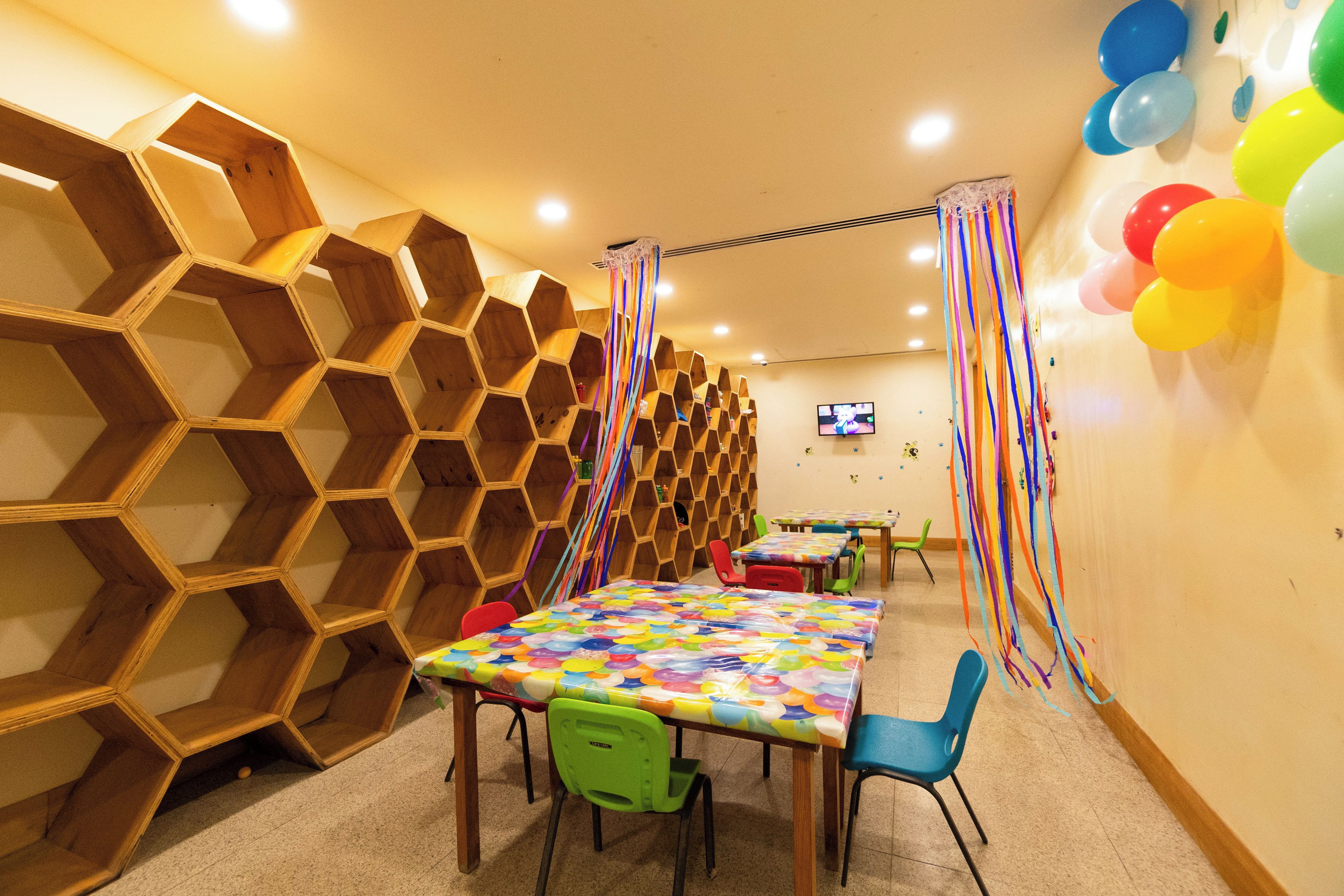 A room with hexagonal wooden shelving, tables with colorful tablecloths, and chairs.