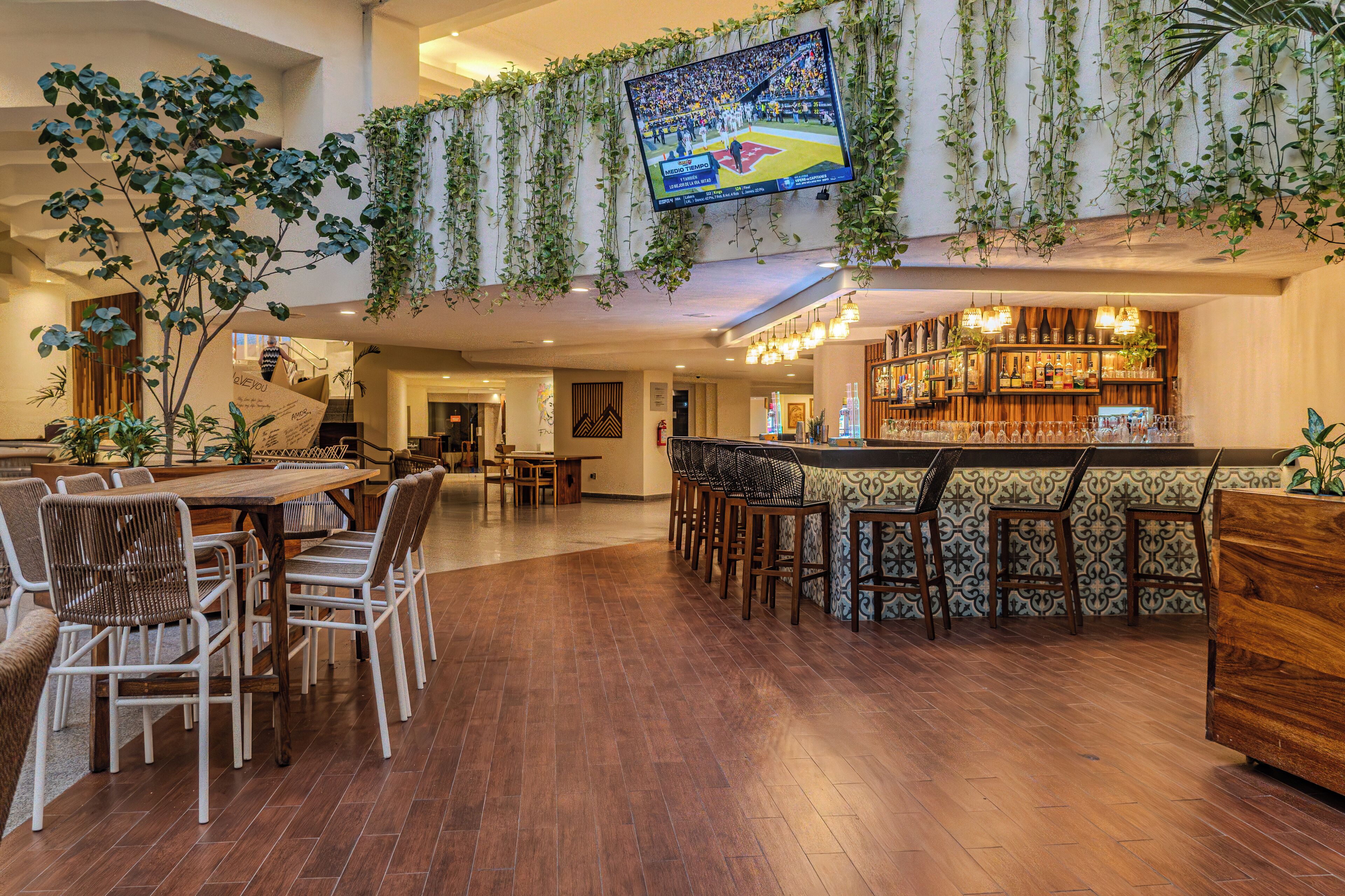 A spacious indoor area with a bar, seating, and a television displaying a sports event.