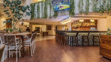 A spacious indoor area with a bar, seating, and a television displaying a sports event.