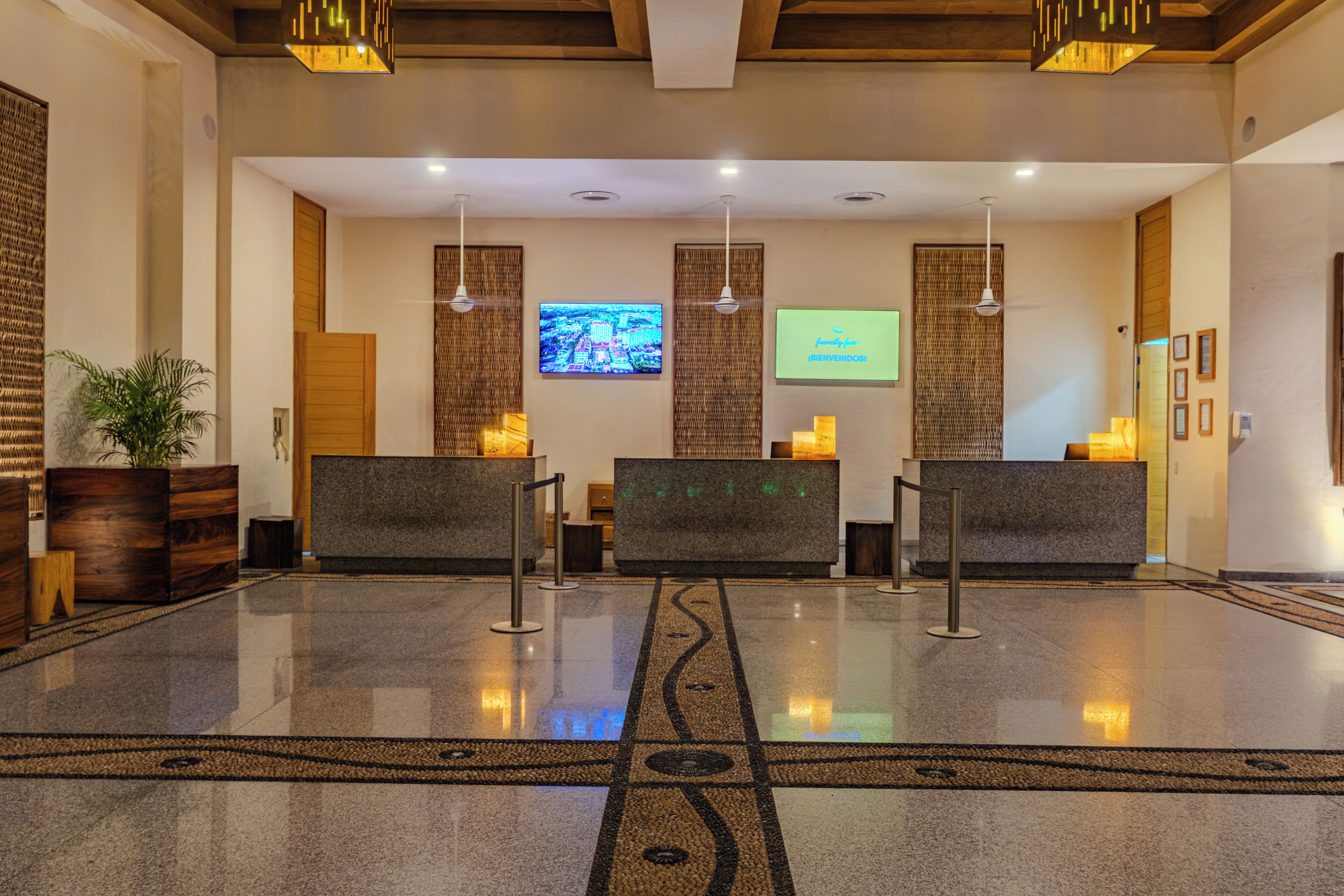 A reception area with a polished floor, two reception desks, a television screen, and a wall-mounted digital display.