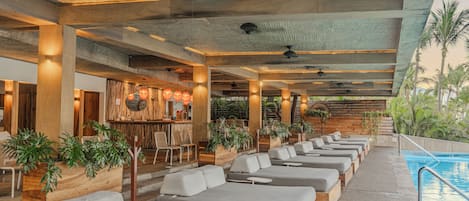 Ein Pool-Lounge-Bereich mit verschiedenen Sitzmöglichkeiten, einer Bar und Blick auf den Pool.