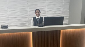 A reception desk with a computer and a phone, a wooden panel design, and a Days Inn by Wyndham sign on the floor. - Days Inn & Suites by Wyndham Summerside (Summerside)