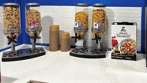 A breakfast station with multiple dispensers for Kellogg's cereals, a sign stating "Breakfast is on us," and a Quaker brand cereal box. - Days Inn & Suites by Wyndham Summerside (Summerside)
