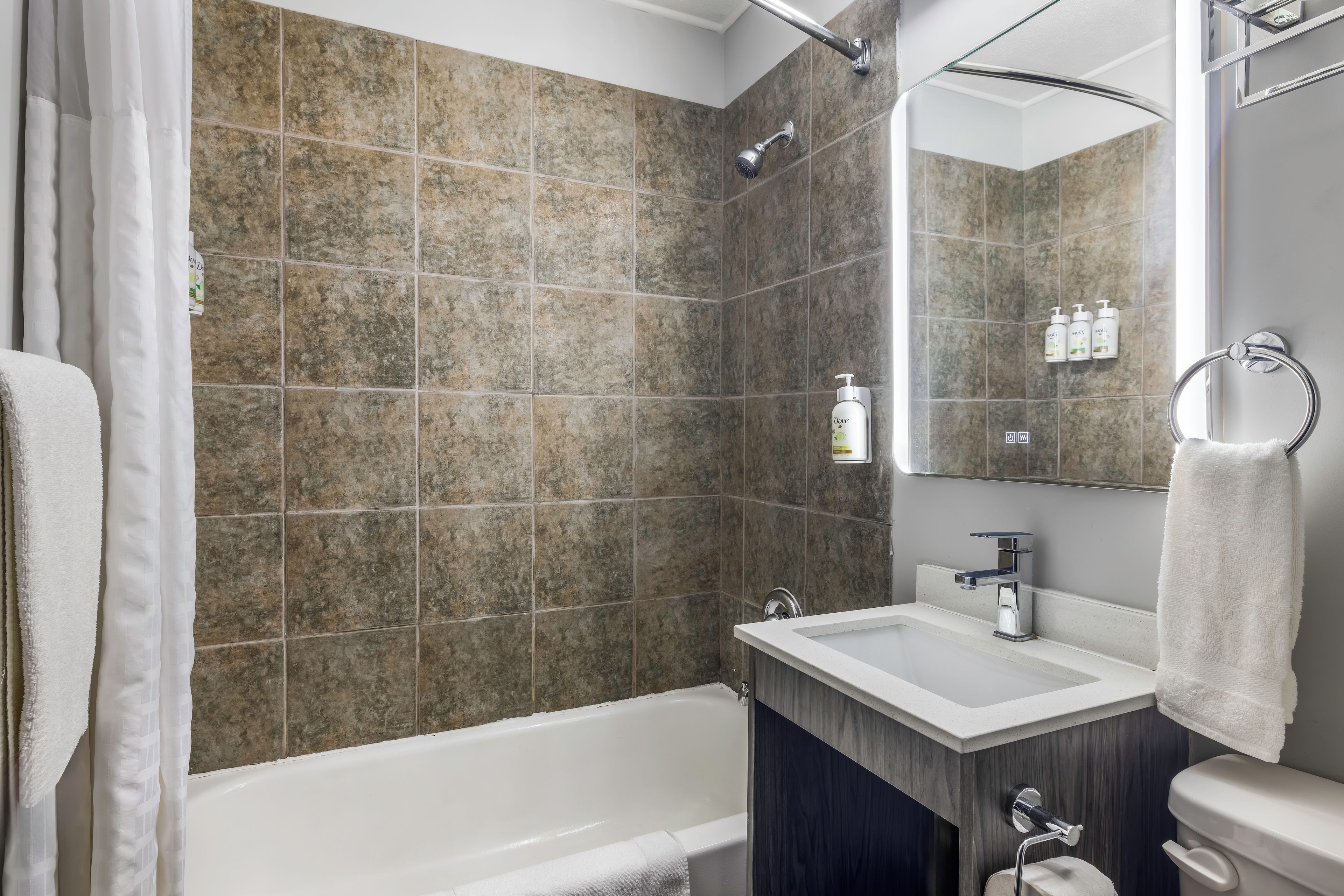 A modern bathroom with a bathtub, a sink, and a mirror.
