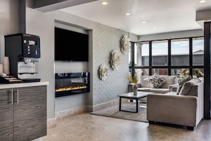 A modern living room with a flat-screen TV, a coffee machine, and a fireplace. - Days Inn & Suites by Wyndham Summerside (Summerside)