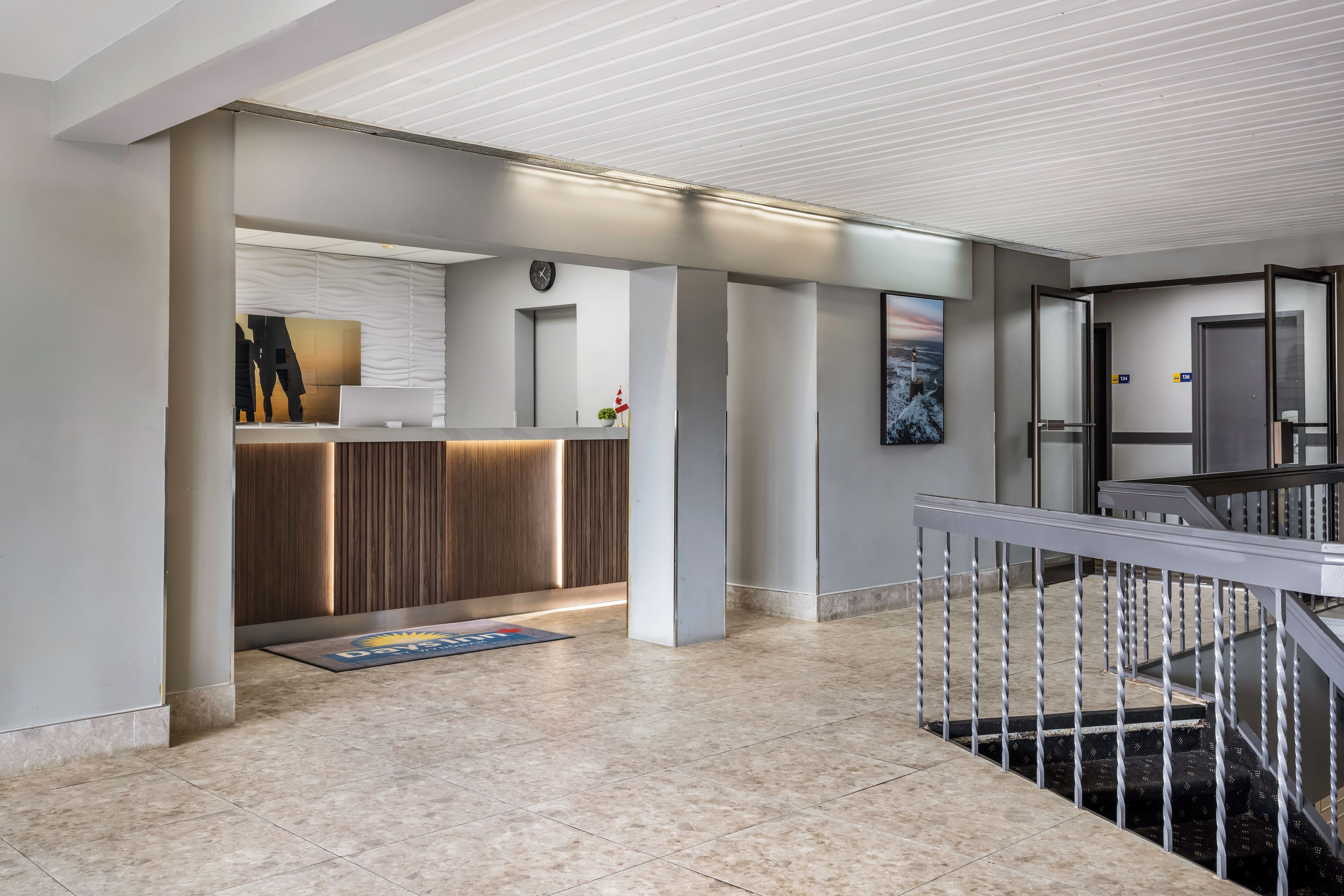Un moderno vestíbulo de hotel con una recepción, un reloj y una escalera.