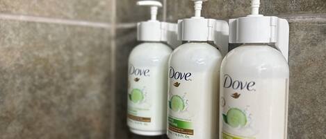 Drei Dove-Shampooflaschen an einer gefliesten Wand angebracht.