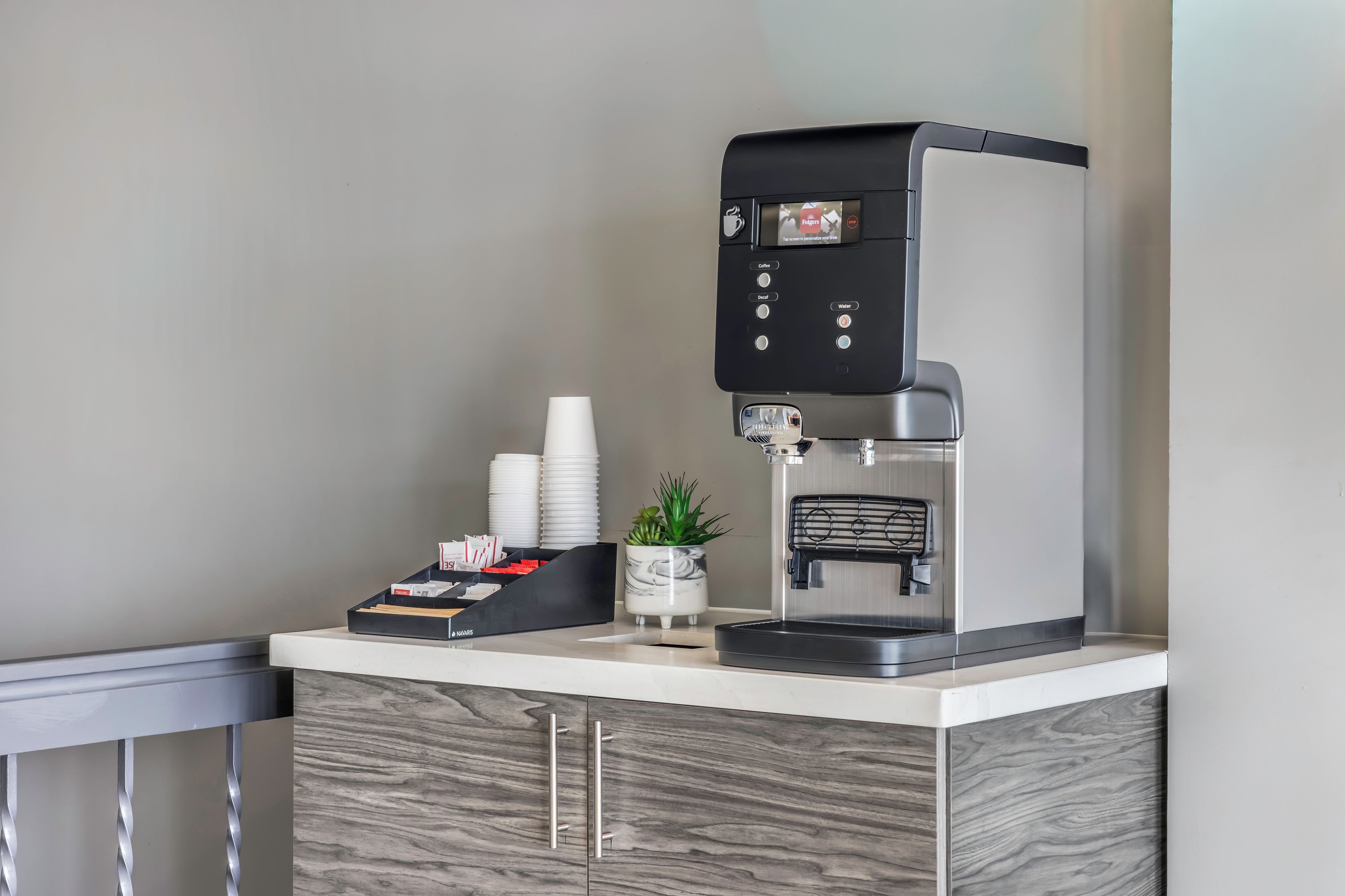 A coffee machine with a digital display, a water dispenser, and a coffee pod holder on a counter.