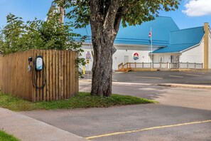 A building with a blue roof, a wooden fence, and a tree in the foreground. - Days Inn & Suites by Wyndham Summerside (Summerside)