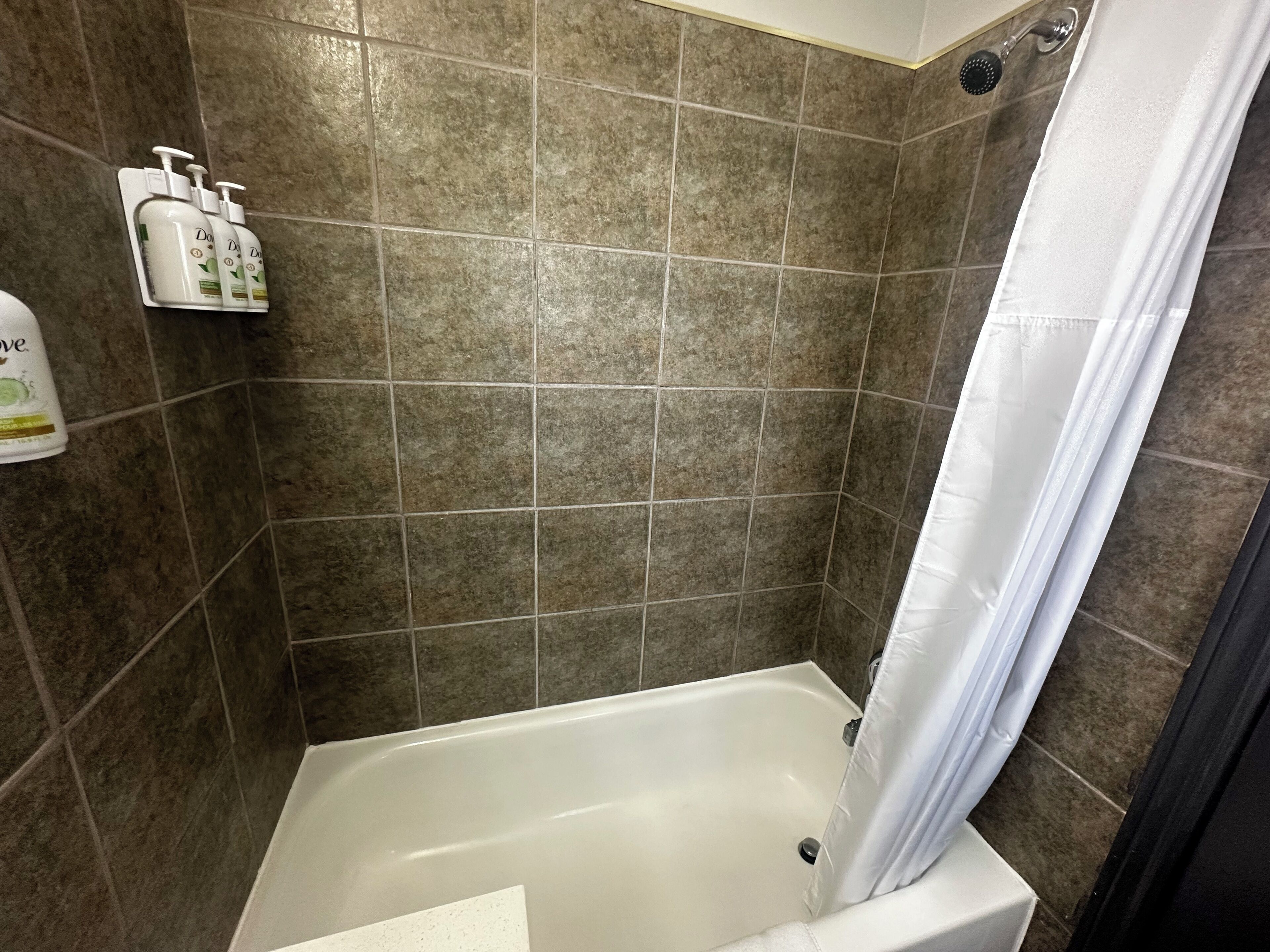 A bathroom with a bathtub, tiled walls, and a shower curtain.