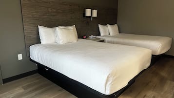 Une chambre d’hôtel avec deux lits, une tête de lit en bois, une table de chevet avec une lampe et une horloge.