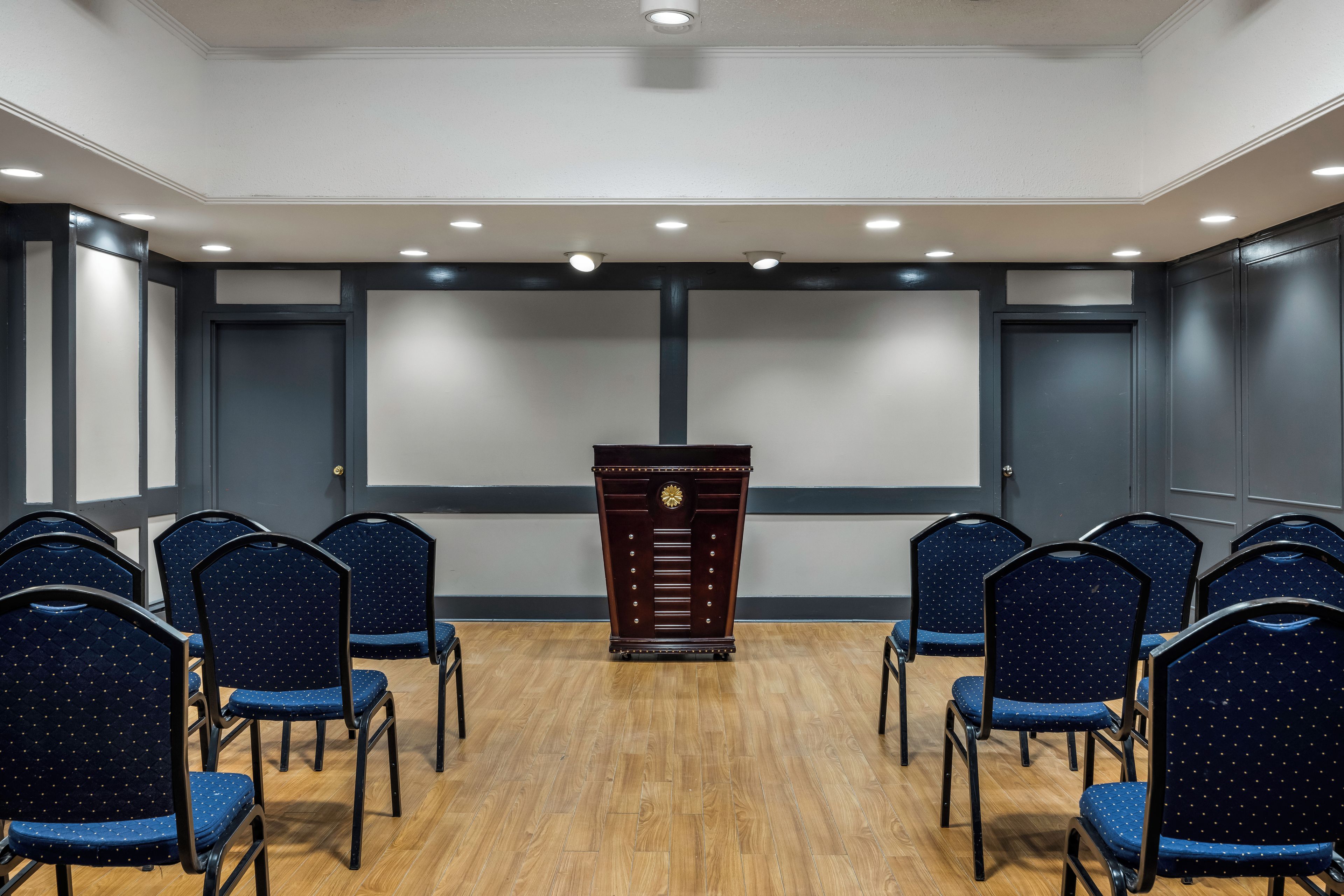 Un salón de conferencias con un atril, sillas y una pantalla grande.