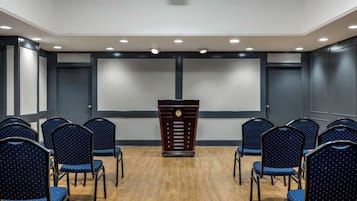 Un salón de conferencias con un atril, sillas y una pantalla grande.