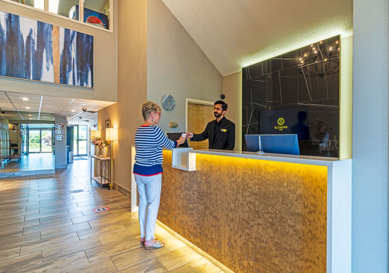 A reception area with a wooden reception desk, a large abstract painting on the wall, and a modern interior design.