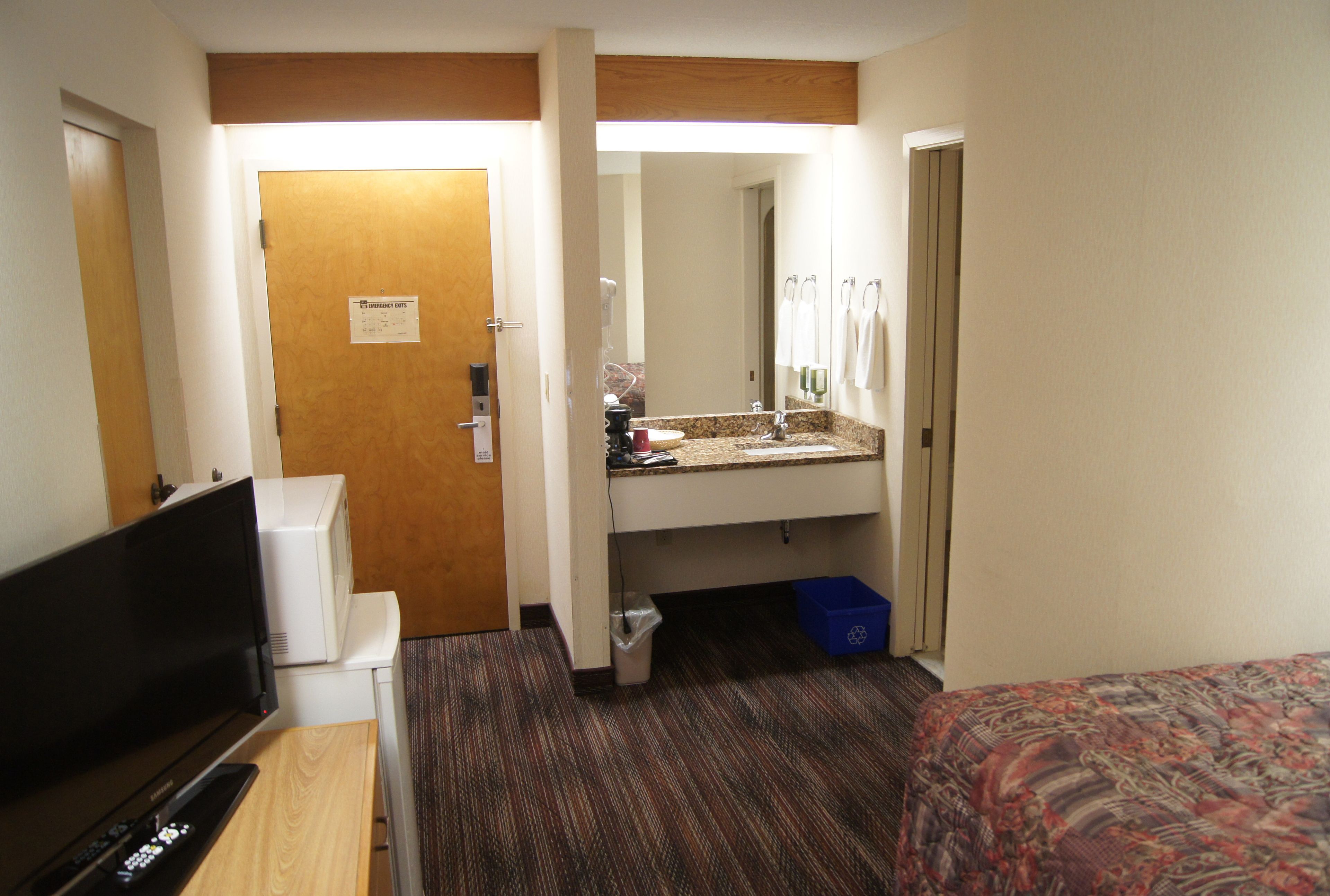 Une chambre d’hôtel équipée d’une télévision, d’un lavabo, d’un miroir et d’un lit.