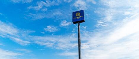 A sign for Slumber Inn against a clear blue sky.