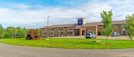 A building with a sign reading "SLUMBER" on the roof, a parking lot with cars, and a grassy area in front.