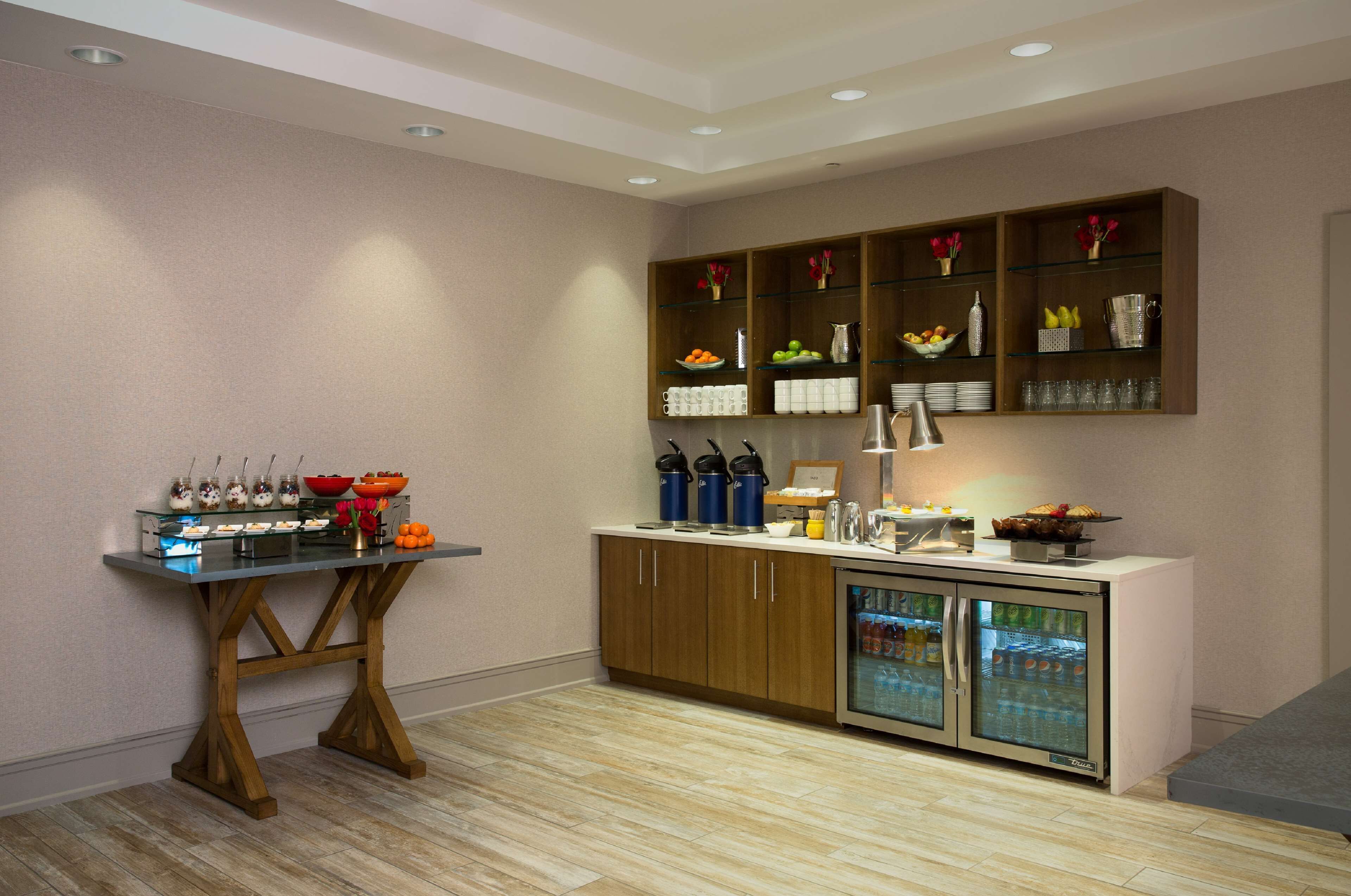 A modern kitchen with a glass-top table, wooden cabinets, and a built-in refrigerator.